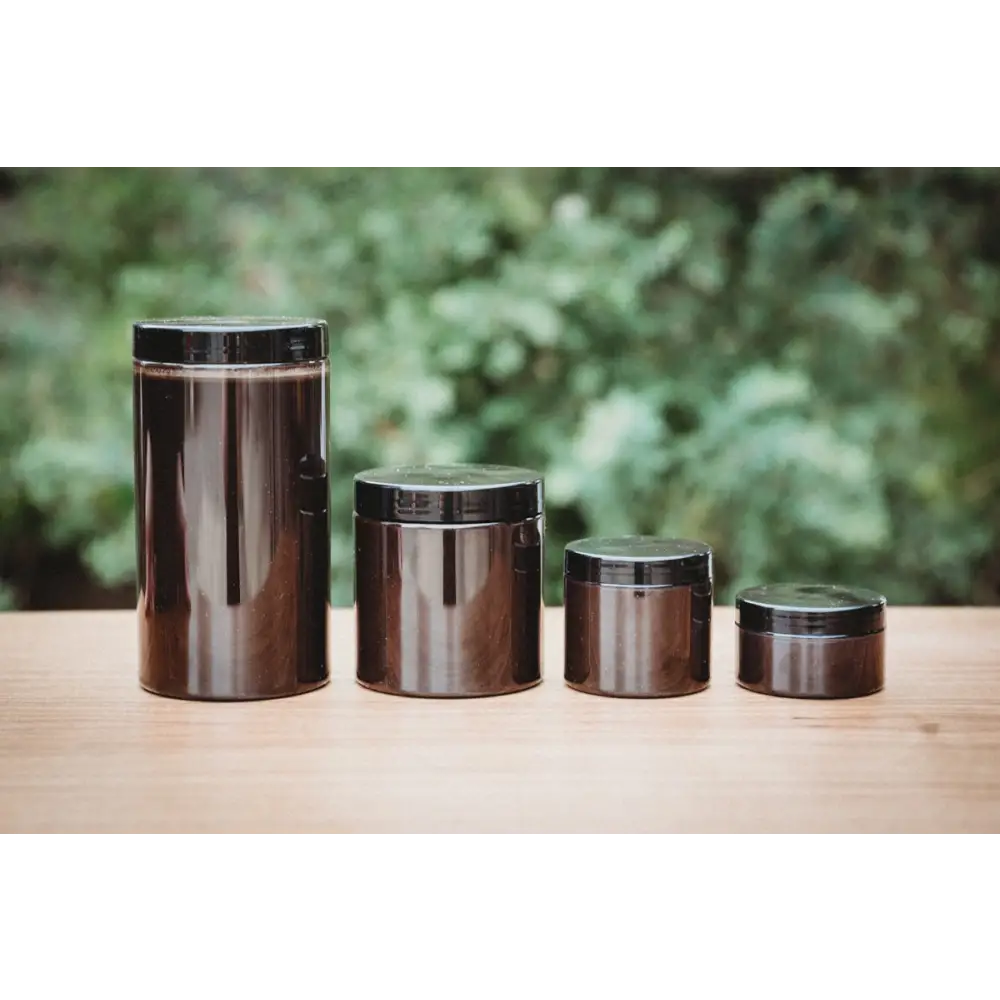 Soil Smiths The Goop — four sealed amber Soil Smiths jars in graduated sizes on a wooden surface