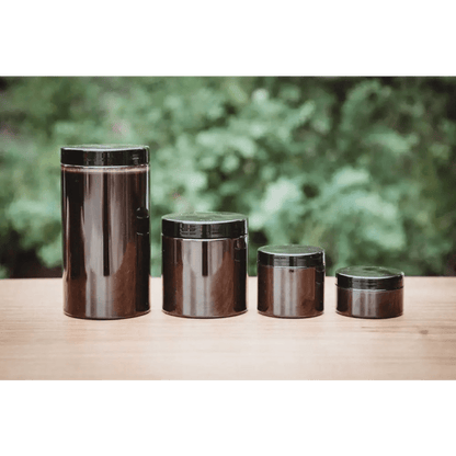 Soil Smiths The Goop — four sealed amber Soil Smiths jars in graduated sizes on a wooden surface